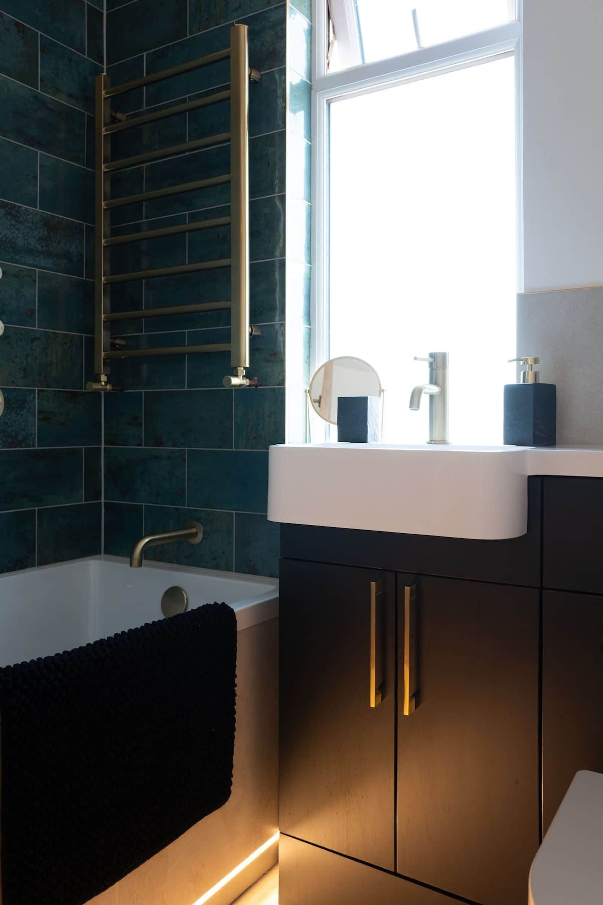 A modern bathroom with a bathtub, a window, a sink with a mirror, and a towel rack.