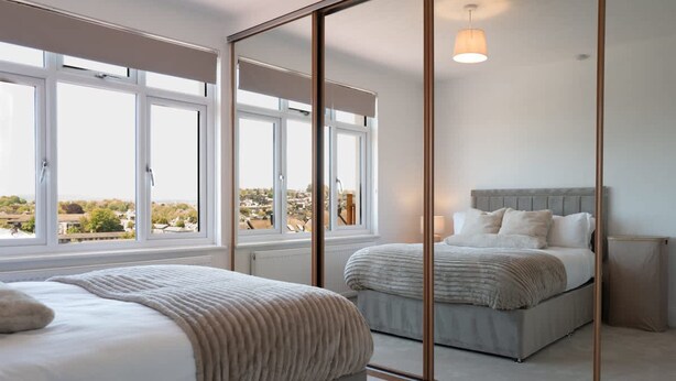 Ein Schlafzimmer mit zwei Betten, einem großen Spiegel und Blick ins Freie.