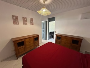 Une chambre à coucher avec une couvre-lit rouge, des armoires en bois et un luminaire au plafond.