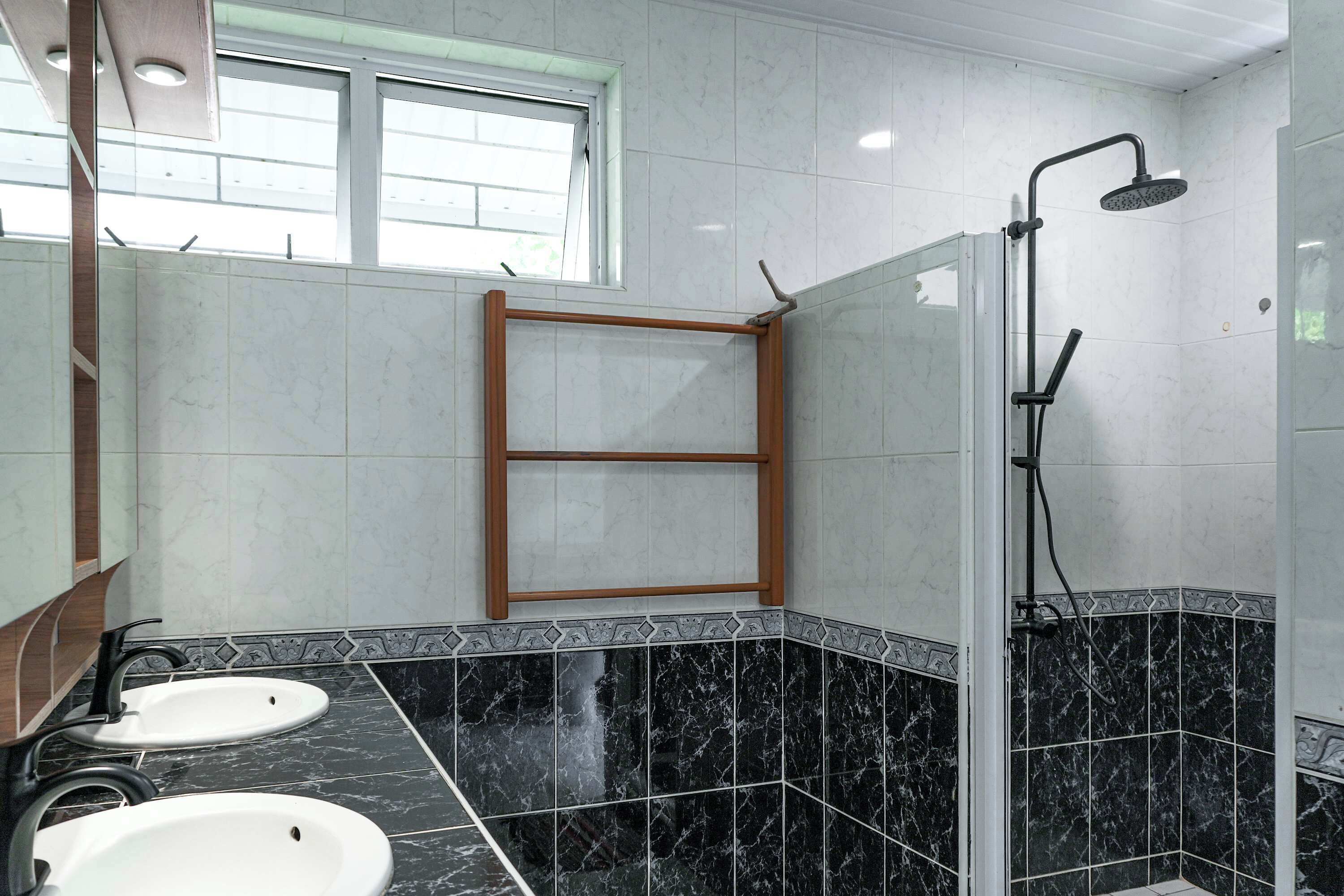 Une salle de bain avec deux lavabos, une douche et une fenêtre.