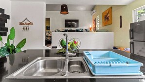 Uma cozinha moderna com uma pia de aço inoxidável, um escorredor de louça azul e um enfeite na parede.