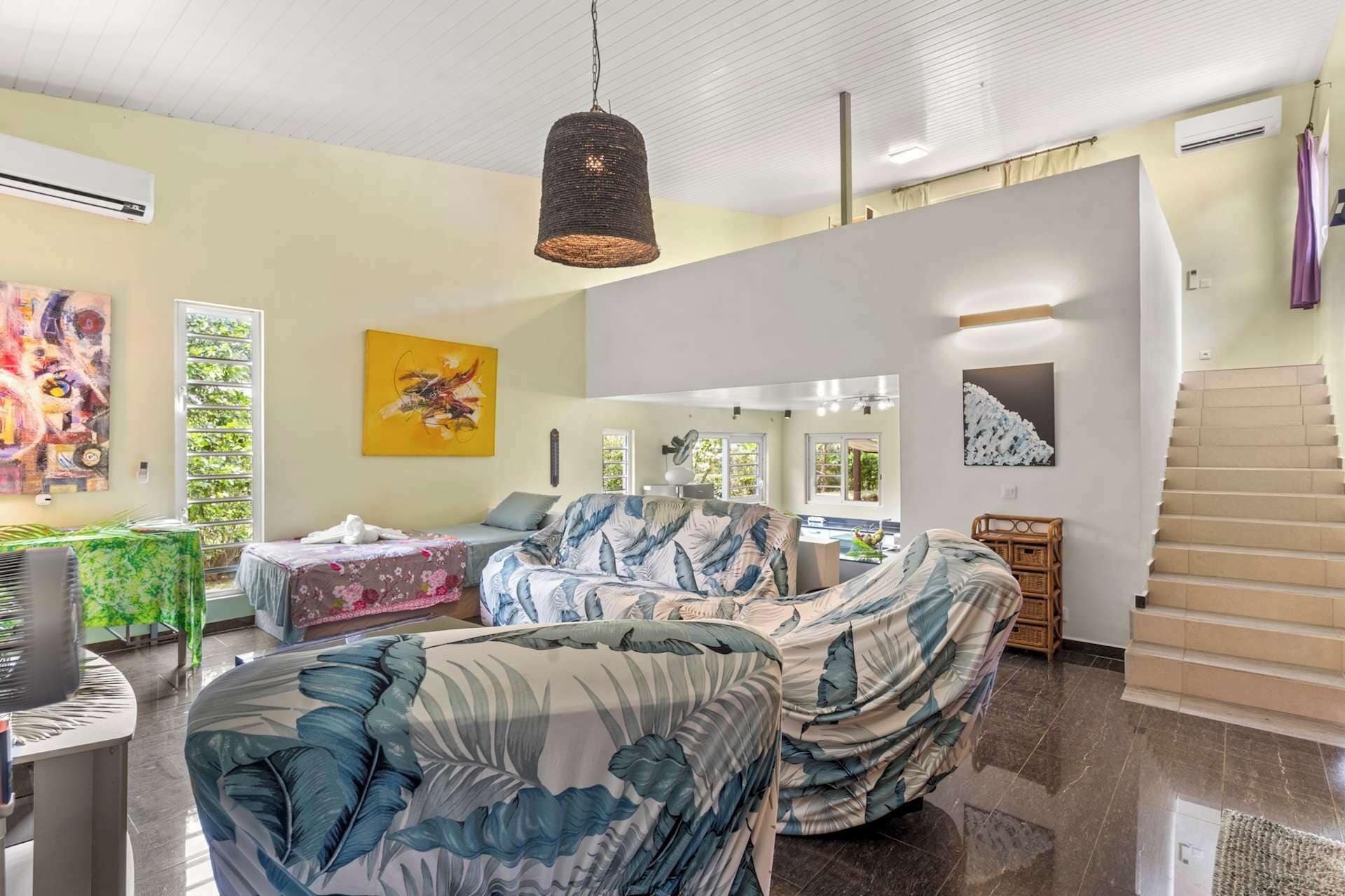 A spacious living area with a large sofa, a hanging light fixture, and artwork on the walls.