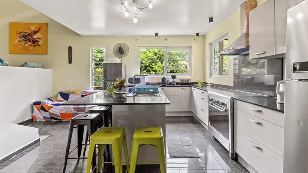 Cozinha moderna com ilha central, eletrodomésticos de aço inoxidável e janela que permite entrada de luz natural.