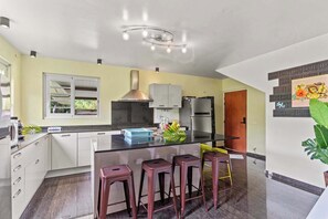 Una cuina moderna amb una illa central, tamborets de bar, un frigorífic d'acer inoxidable i una finestra amb vista.