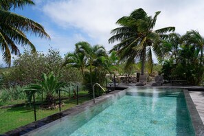 A pool with clear water, surrounded by palm trees and greenery. - Dolce Vita Villa Moorea (Moorea-Maiao)