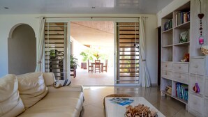 A living room with a sofa, a coffee table with a decorative bowl, and a bookshelf with books and decorative items. - Dolce Vita Villa Moorea (Moorea-Maiao)