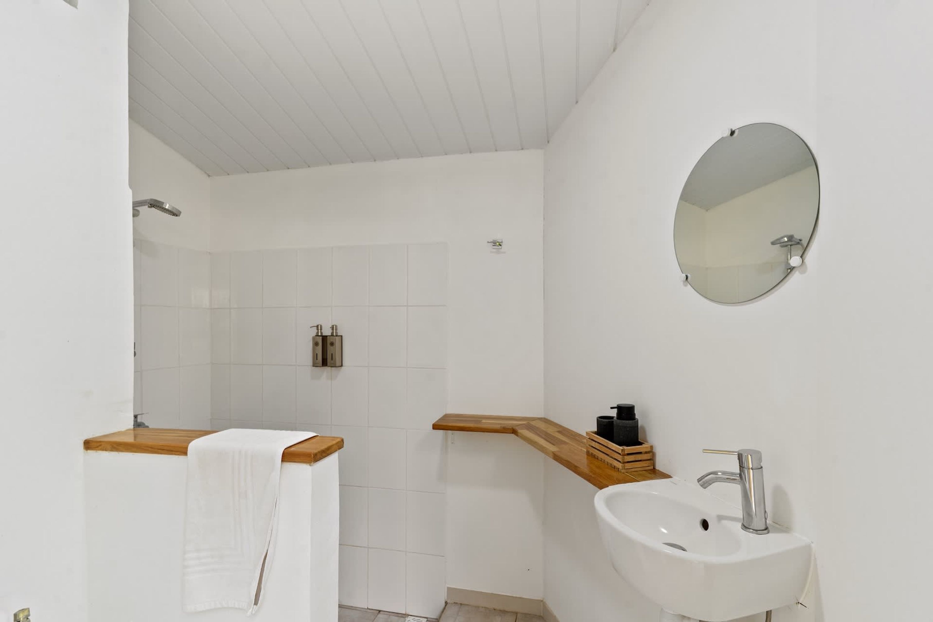 Ein Badezimmer mit Dusche, Waschbecken, Spiegel und Handtuchhalter.