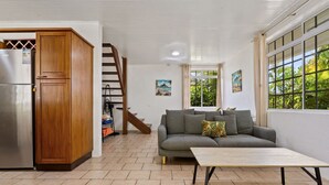 A living room with a grey sofa, wooden cabinet, and a table. - Moorea Mahana House With Private Canal to Lagoon (Moorea-Maiao)