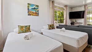 A hotel room with two beds, a sofa, a TV, and a painting on the wall. - Moorea Mahana House With Private Canal to Lagoon (Moorea-Maiao)
