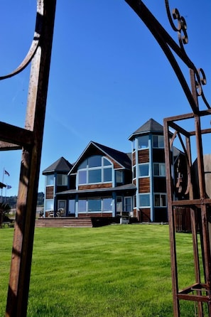 A two-story house with a large front lawn and a metal gate. - Stunning Beachside Vacation Rental for Family or Group Glamping Escapes to Alaska (Homer)