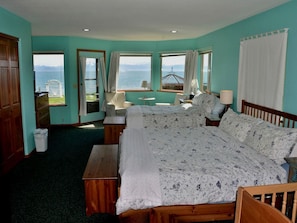 A bedroom with a large bed, two bedside tables, a chair, and a view of the sea. - Stunning Beachside Vacation Rental for Family or Group Glamping Escapes to Alaska (Homer)