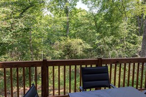 A wooden deck with a table and chairs, surrounded by dense green foliage. - Perfect Cabin Retreat for Four in Livingston, Texas (Livingston)