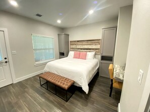 A bedroom with a bed, bench, bedside tables, and a window with blinds. - Perfect Cabin Retreat for Four in Livingston, Texas (Livingston)