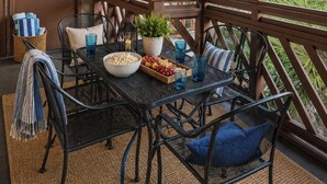 Een overdekt buiten-eetgedeelte met een tafel, stoelen en uitzicht op groen.