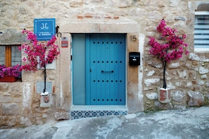 Un edificio de piedra con una puerta azul, número 15, y un cartel que indica 'Casa Rural El Mirador'.