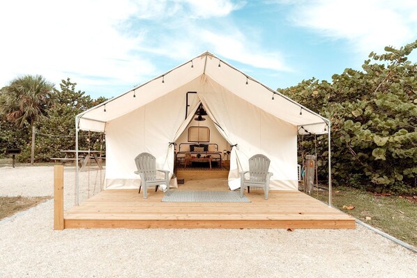 A tent with a wooden deck, two chairs, and a table.
