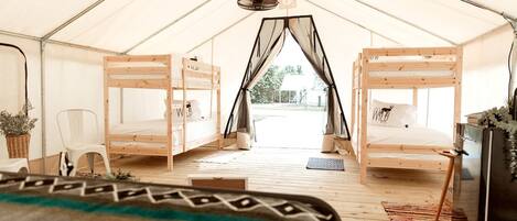 A tent with two bunk beds, a chair, a small table, and a hanging light fixture.