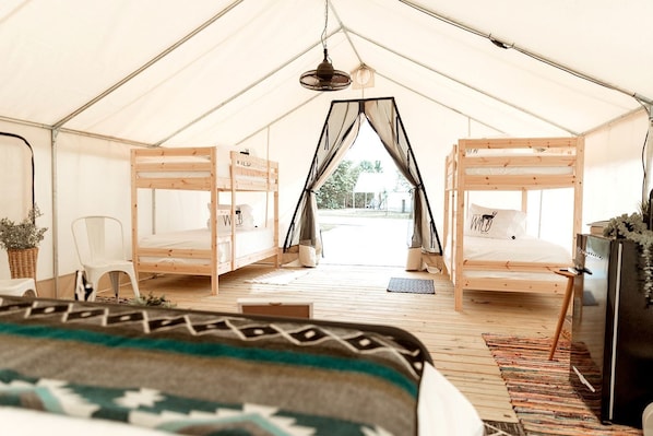 A tent with two bunk beds, a chair, a small table, and a hanging light fixture.
