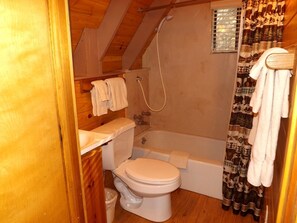 A small, compact bathroom with a toilet, bathtub, and shower. - Charming Equipped Cabin Suitable for Four in Arizona (Flagstaff)