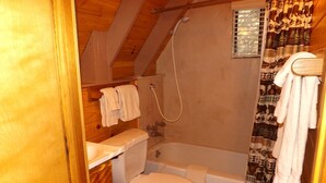 Ett litet, kompakt badrum med toalett, badkar och dusch.