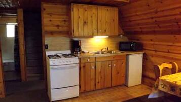 Une cuisine compacte avec des meubles en bois, une cuisinière, un évier et un four à micro-ondes.