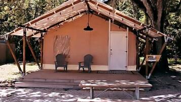 A small, single-room structure with a pitched roof, a door, and a bench outside.