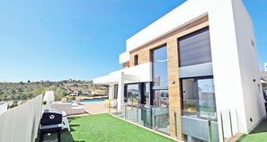 Ein modernes Haus mit Pool, Sitzgelegenheiten im Freien und Blick auf die Hügel.
