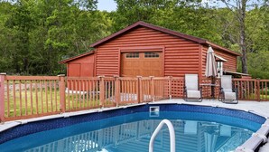 A wooden cabin with a pool, surrounded by a wooden fence and trees. - Luxury Catskills Creekside Cabin | Pool, Sauna & Fire Pit Retreat (Roscoe)