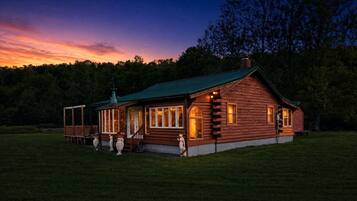 A log cabin with a porch, a covered deck, and a chimney.