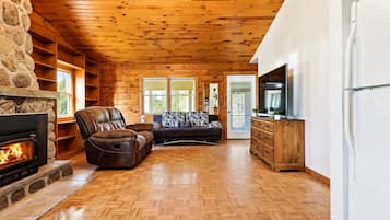 A cozy living room with a fireplace, leather recliner, sofa, and wooden cabinets.
