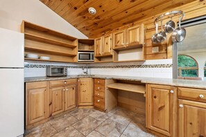 Une cuisine avec des meubles en bois, un four à micro-ondes, un évier et une fenêtre donnant sur un beau paysage.