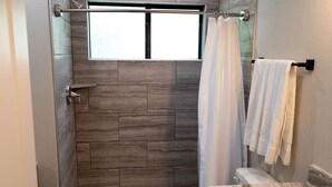 Ein Badezimmer mit Dusche, einem Fenster und einem Handtuchhalter.