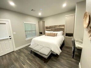 A bedroom with a bed, bedside tables, a window with blinds, and a door. - Quaint Cabin Ideal for a Secluded Getaway in Livingston, Texas (Livingston)