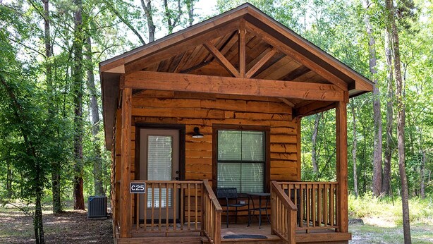 Ein kleines Blockhaus mit Veranda, zwei Fenstern und einer Tür.