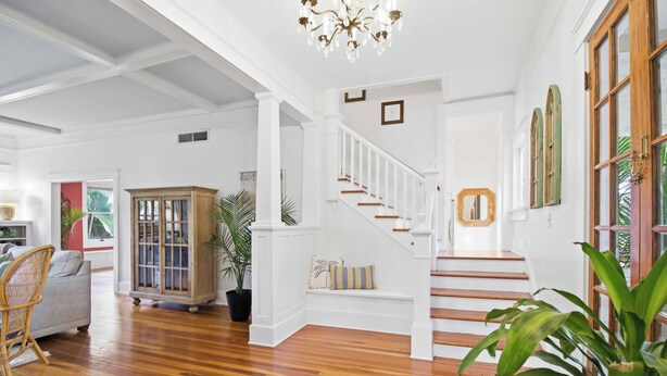 A spacious room with hardwood flooring, a white staircase, and a large window. - The Veranda at Wares Creek - Sleeps 12, Pet-friendly, minutes to Gulf beaches! (Bradenton)
