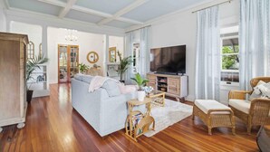 A living room with a sofa, television, wicker furniture, and a bookshelf. - The Veranda at Wares Creek - Sleeps 12, Pet-friendly, minutes to Gulf beaches! (Bradenton)