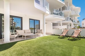 A modern apartment with a balcony, outdoor seating, and a well-maintained lawn. - Elegant Garden Apartment in Higuer n (Fuengirola)