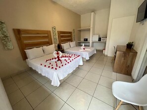 Habitación de hotel con dos camas, un escritorio pequeño, una silla y un televisor.