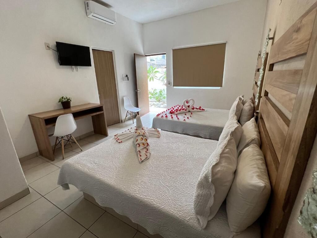 Una habitación de hotel con dos camas, un escritorio, una silla, un televisor y una ventana.