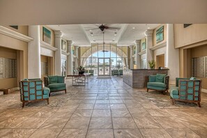 A spacious lobby with a high ceiling, large windows, and a central seating area with chairs. - Spectacular view of the Gulf and just steps away from the pool and beach! (Miramar Beach)