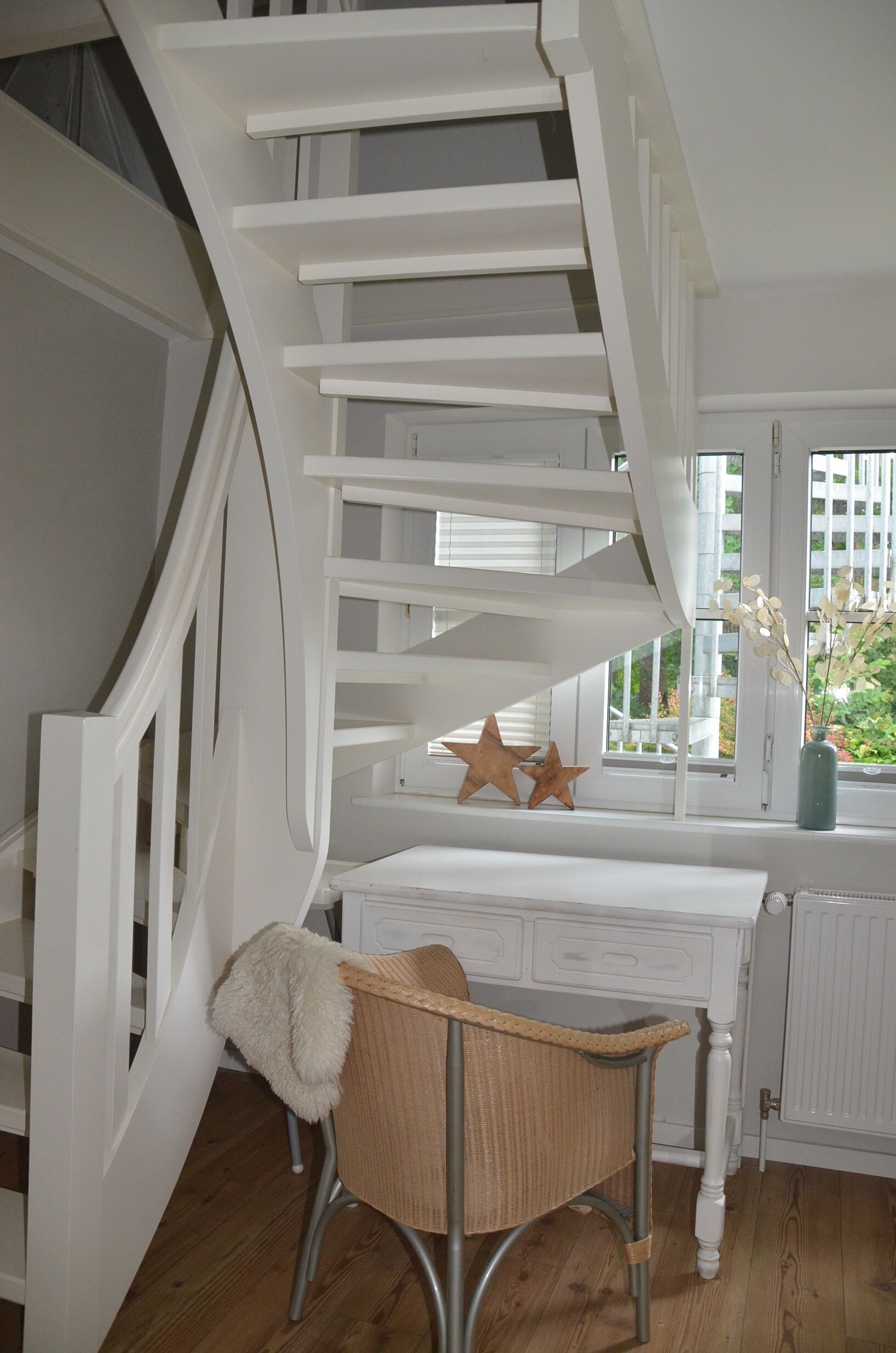 Eine weiße Treppe führt zu einer Plattform mit einem Korbstuhl und Sterndekorationen.