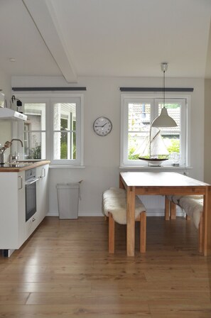 Une cuisine avec des meubles de rangement en bois, un évier et une fenêtre décorée avec un motif de voilier.