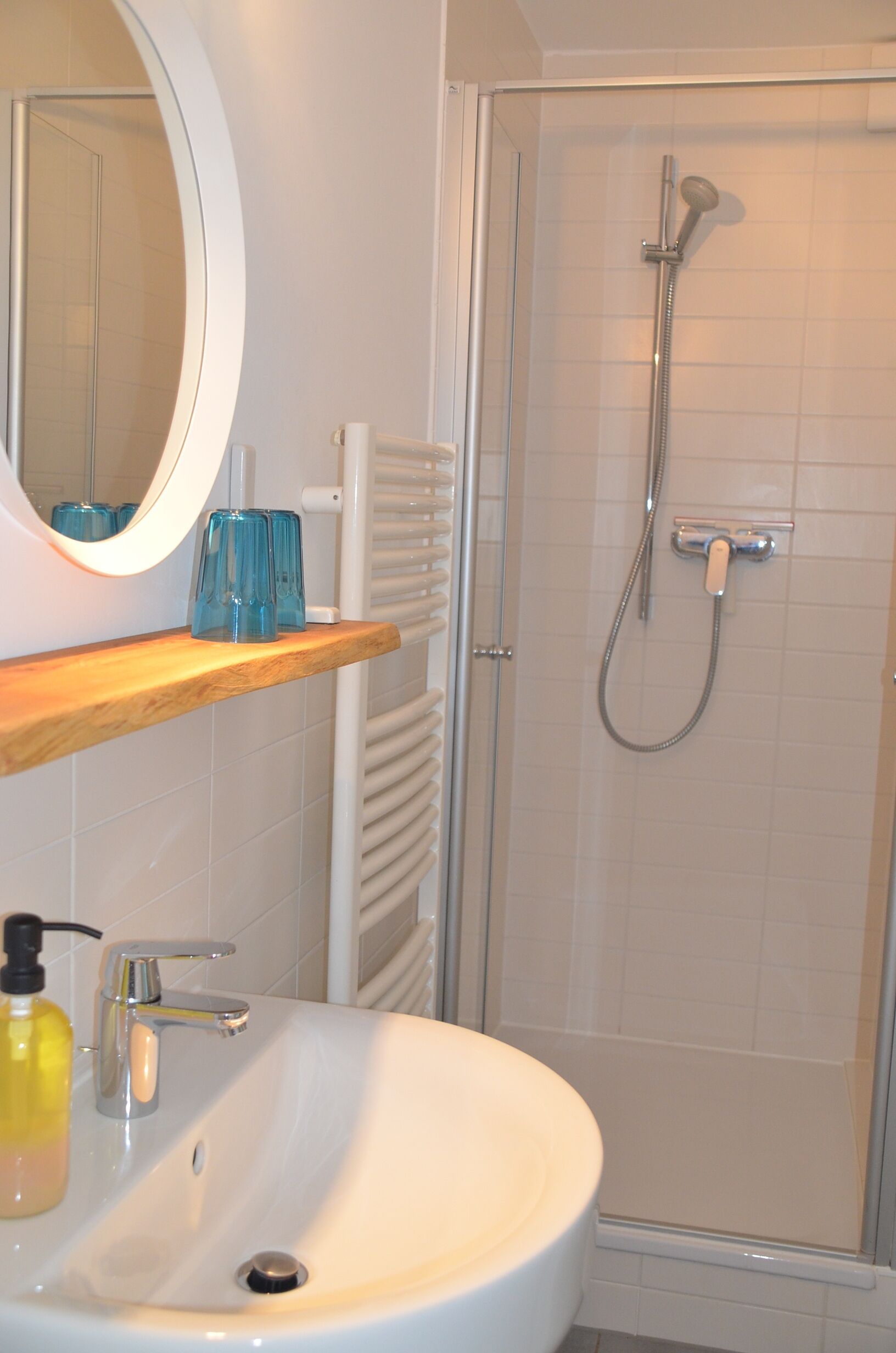 A bathroom with a white sink, a mirror, a shower, and a towel rack.