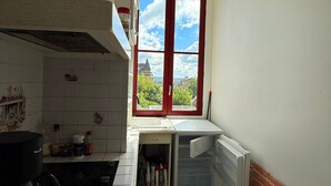 Una cocina con ventana, microondas, cafetera y refrigerador.
