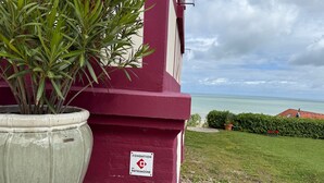 Un edificio con fachada roja, un letrero que dice 'FONDATION du Patrimoine' y vista al mar.