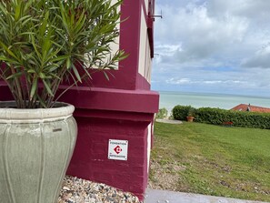Ein Gebäude mit roter Fassade, einem Schild mit der Aufschrift 'FONDATION du Patrimoine' und Blick aufs Meer.