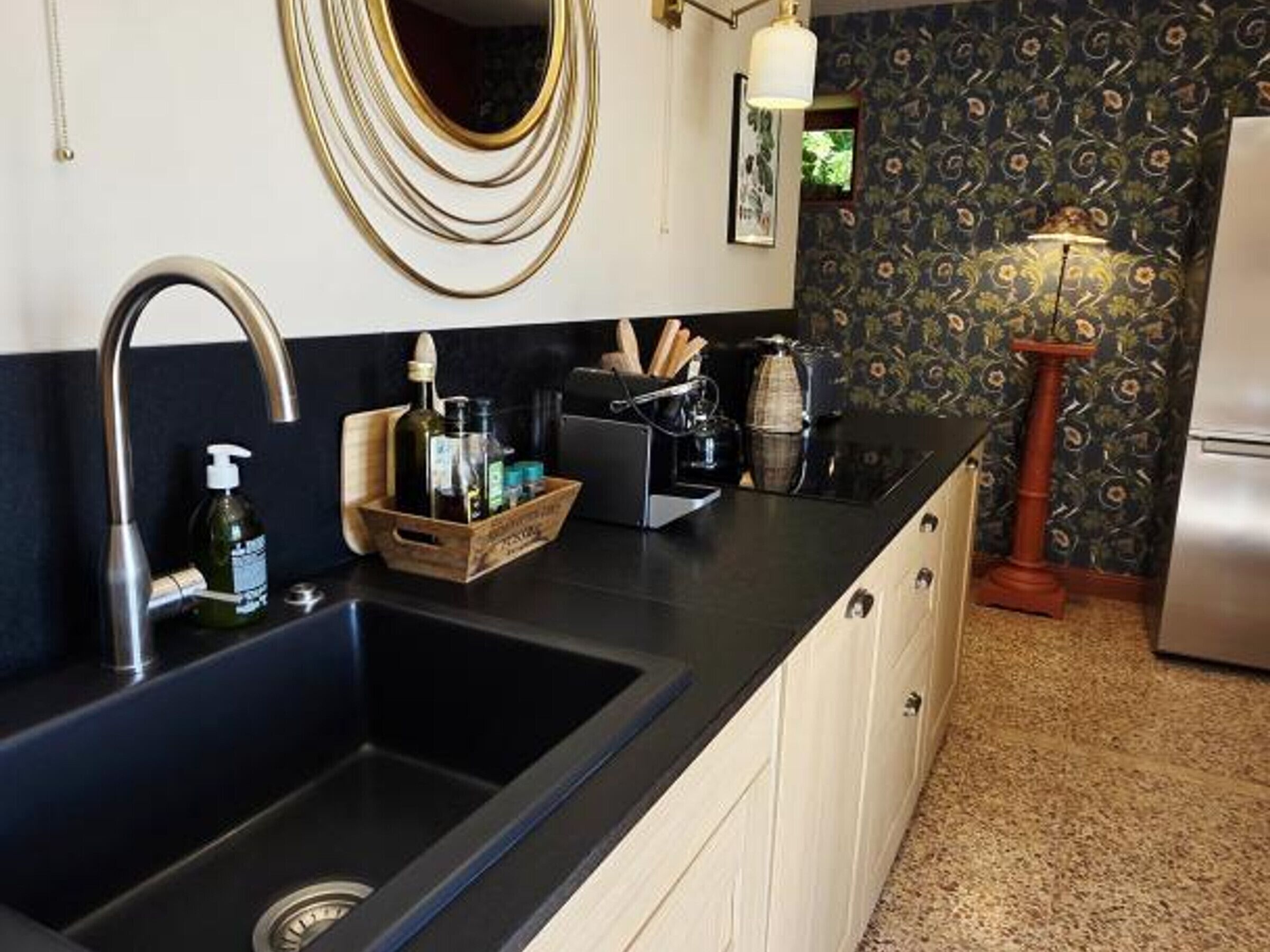 Una cocina con un lavamanos doble, encimera de madera y un espejo decorativo.