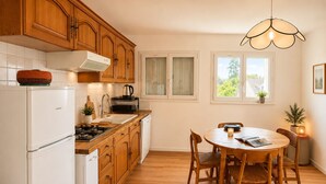 Una cocina con alacenas de madera, un refrigerador blanco, una estufa y una mesa de comedor con sillas.