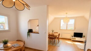 Una sala moderna con comedor, televisor y candelabro.