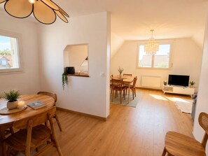 A modern living room with a dining area, a TV, and a chandelier. - Spacious apartment in countryside - 4 guests (Villers-sur-Mer)